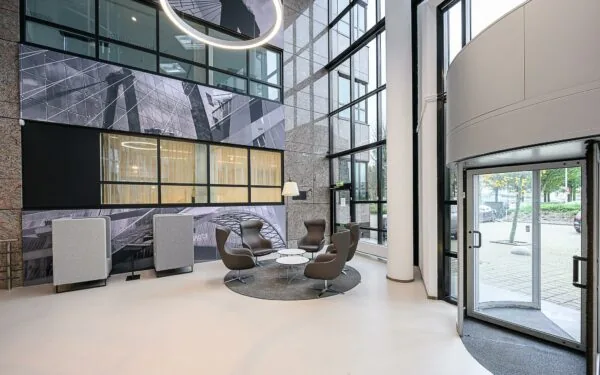 Moderne ontvangsthal van het Rivium Quadrant met designstoelen, glazen gevel en kunstzinnige wanddecoratie.